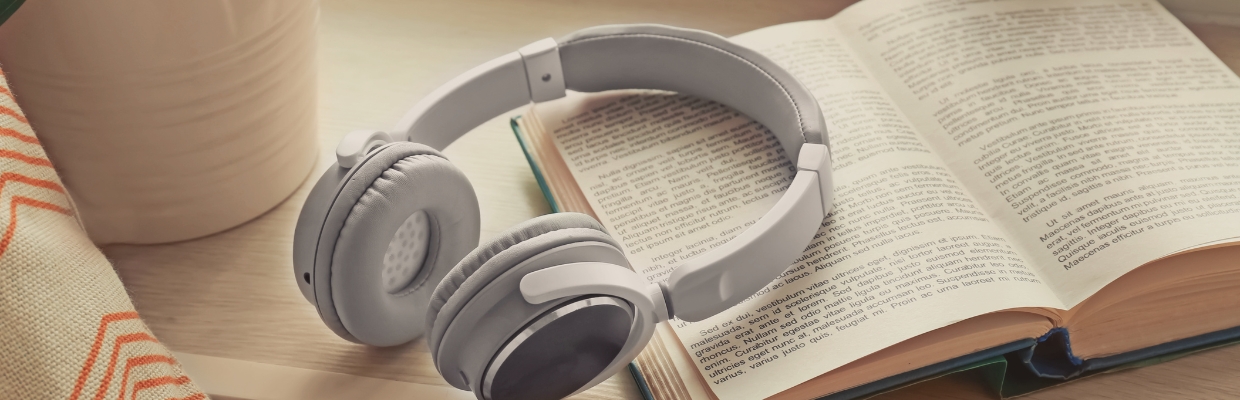 White wireless headphones laying on top of an open book