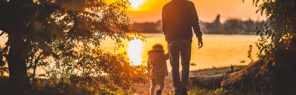 Father and small child walking toward the sunset