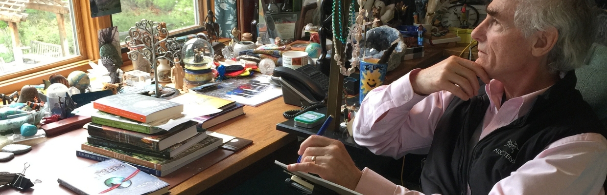 T. A. Barron sitting at his writing desk, looking our of a window in reflection