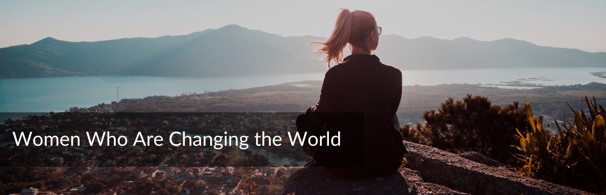 real women heroes — a young woman standing at a mountain's edge, looking out over a vast wilderness landscape